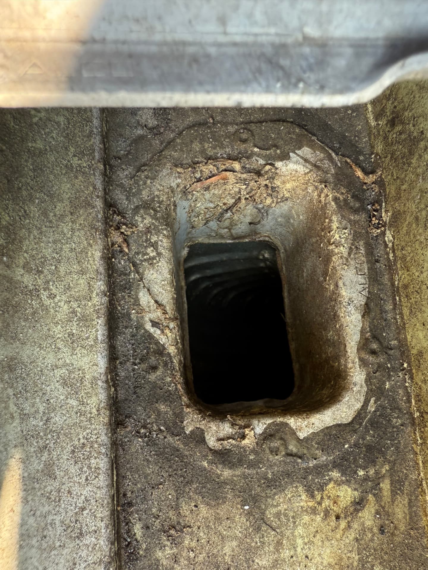 Close-up of a gutter downspout opening showing the interior channel