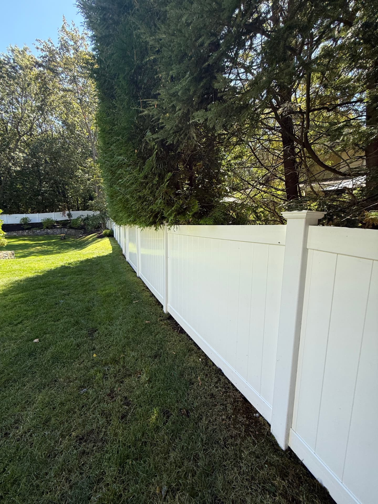 The same long vinyl fence restored to bright white after professional washing